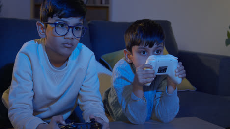 Two-Young-Boys-At-Home-Playing-With-Computer-Games-Console-On-TV-Holding-Controllers-Late-At-Night-5